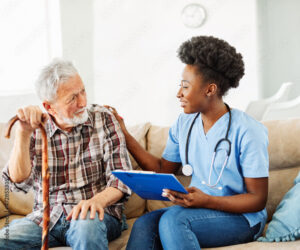 A nurse goes over paperwork with an elderly man holding a wooden cane.