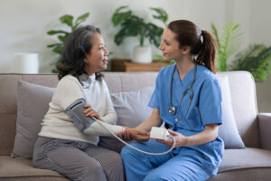 A nurse takes an elderly patients blood pressure in the comfort of the patient's home.