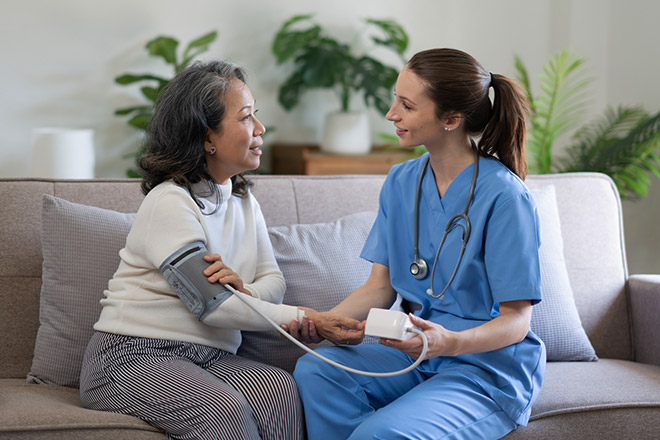 A nurse takes an elderly patients blood pressure in the comfort of the patient's home.